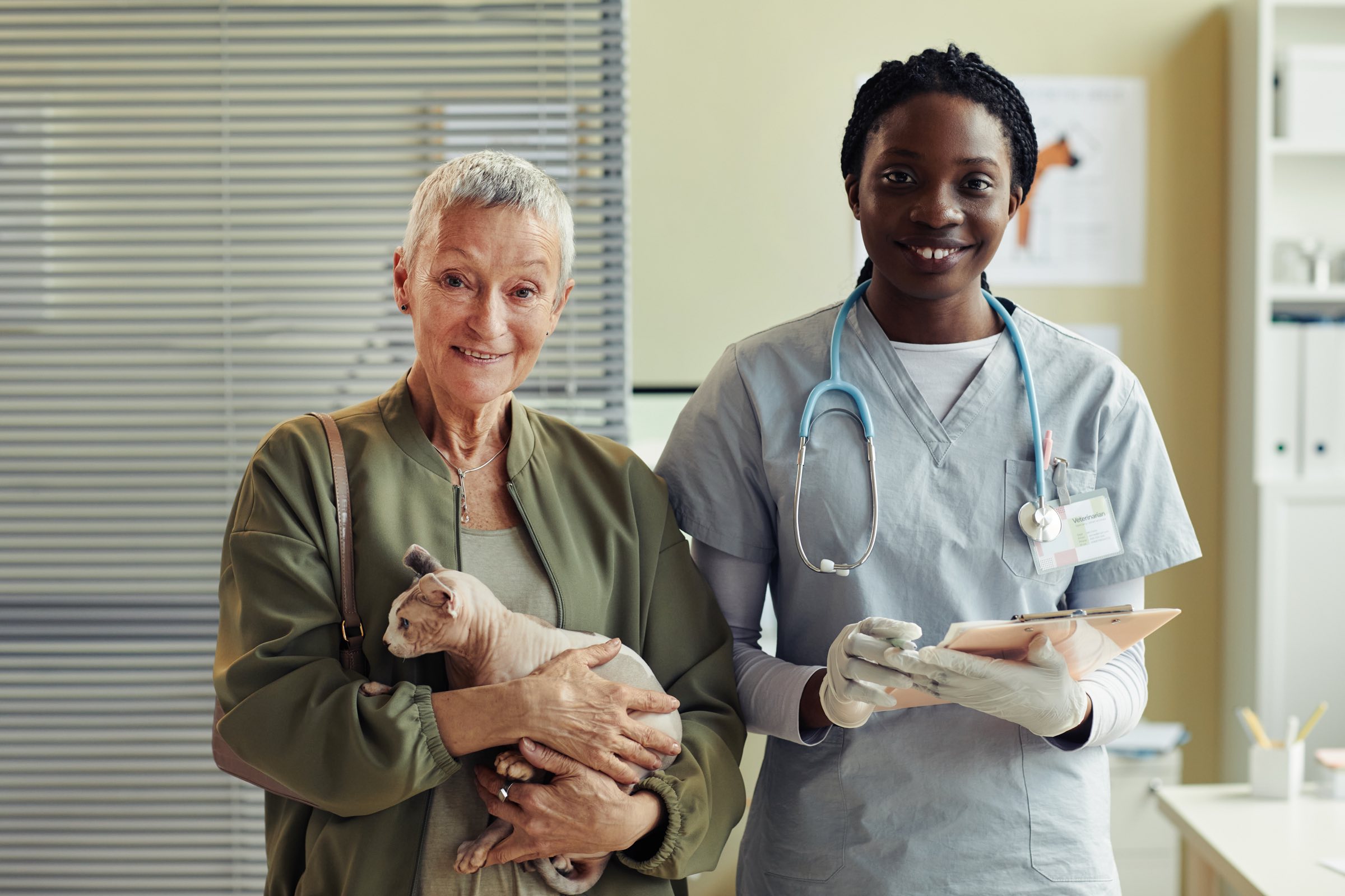 A pet owner holding their cat, smiling with the veterinarian after a consultation